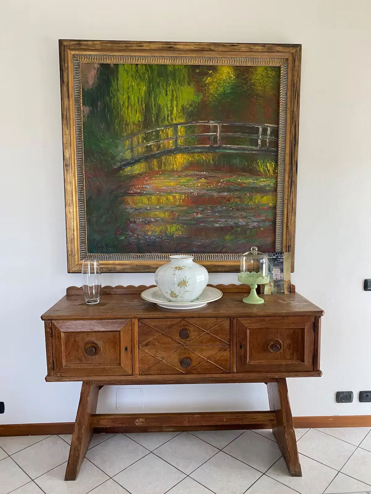 Credenza con vaso in ceramica sotto un dipinto paesaggistico