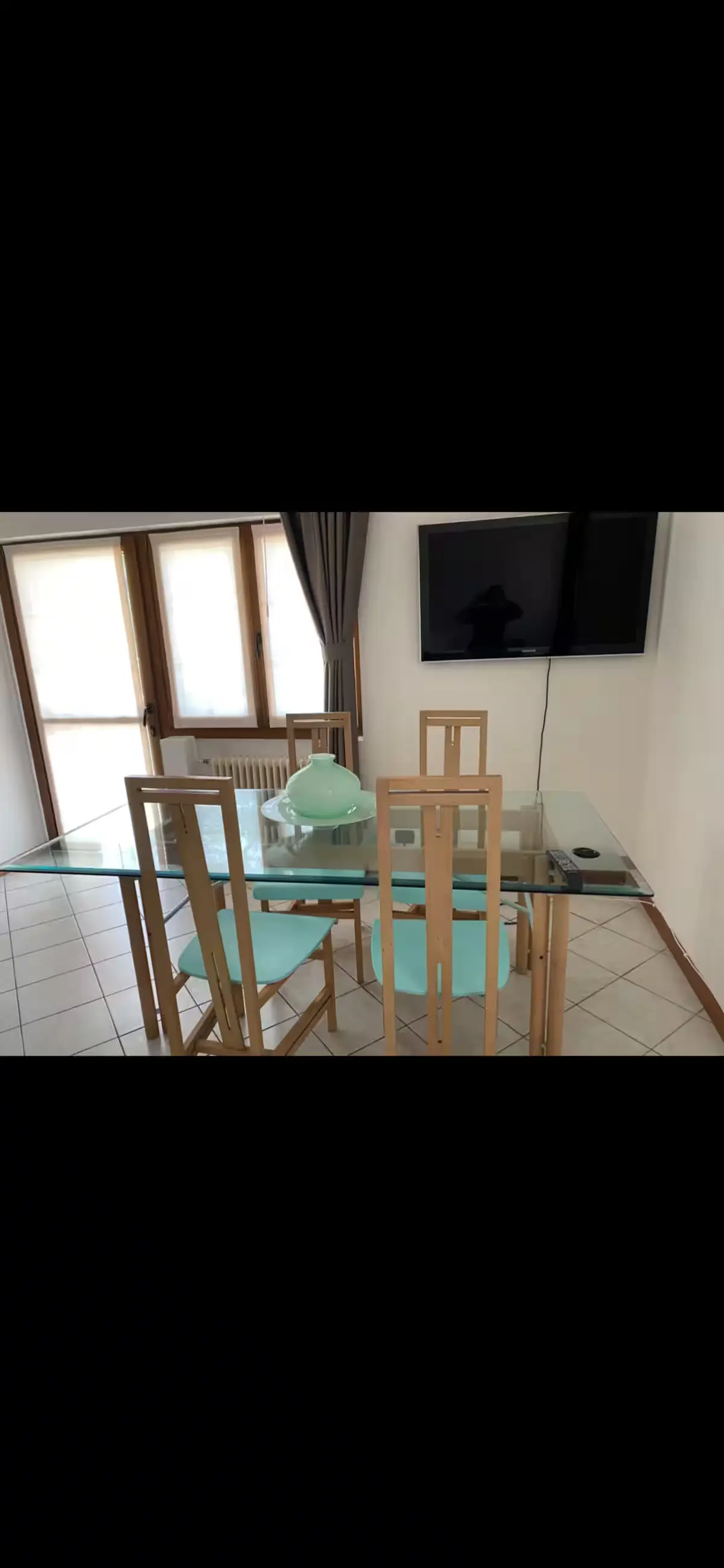 Dining area with glass table and wall-mounted TV