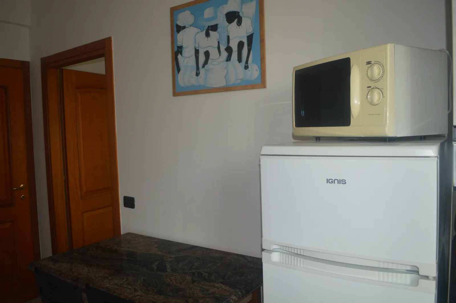 Cucina con frigo, microonde e quadro a parete