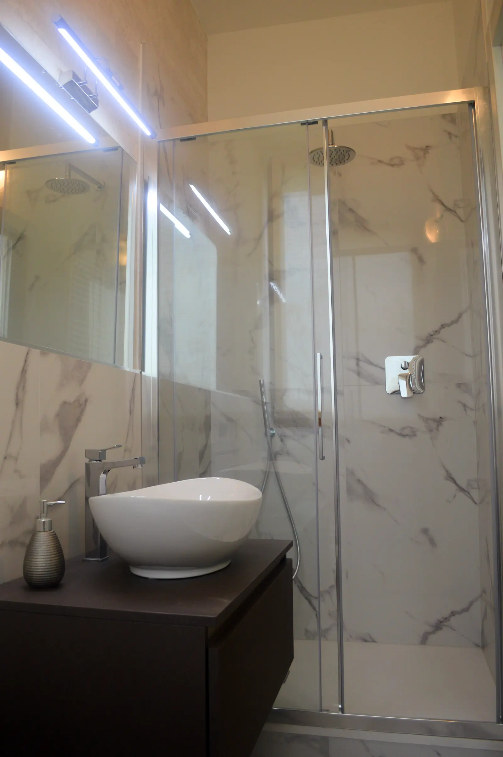 Box doccia in vetro e lavabo a bacinella della suite