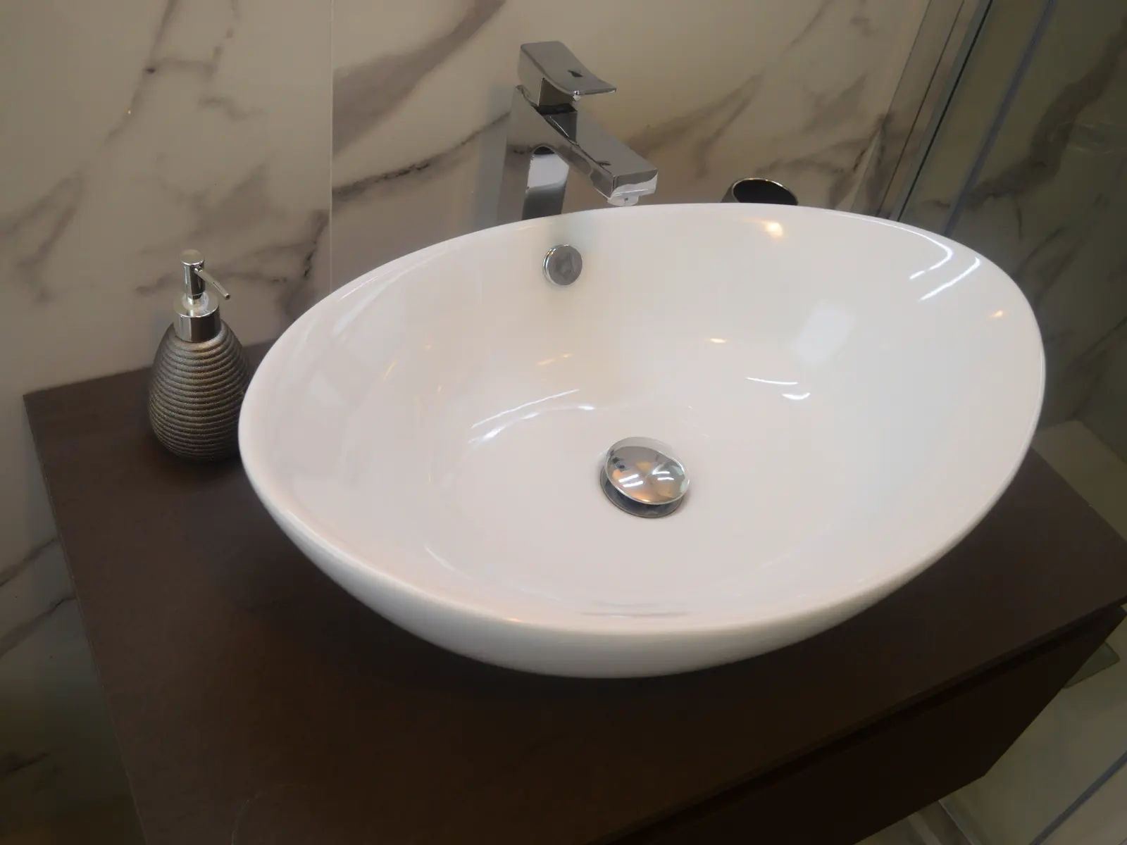 Lavabo ovale bianco su mobile scuro