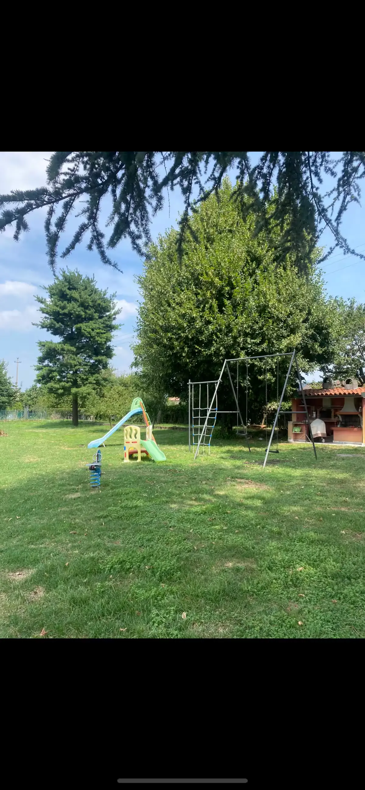 Garden slide, swing set, and wooden shed in summer